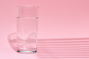 Glass of water on a pink background