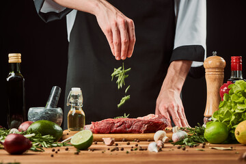 Chef sprinkles rosemary over a piece of beef