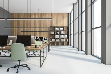 Open space office with computers and green chairs, a bookshelf on a white floor
