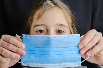 Mother is holding mask in front of her child. Concept and new normal.