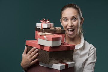 Happy young woman holding a lot of gift boxes