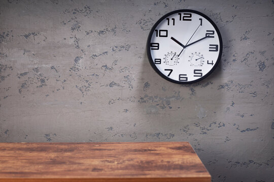 wall clock and table near concrete background