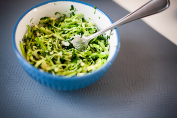 Vegan salad with chopped cabbage, parsley and dill in bowl with fork on gray napkin.