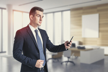 Serious businessman with smartphone in office