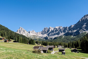 Fototapeta na wymiar Tal mit Holzhütten im Hintergrund Berge und Bäume in Südtirol