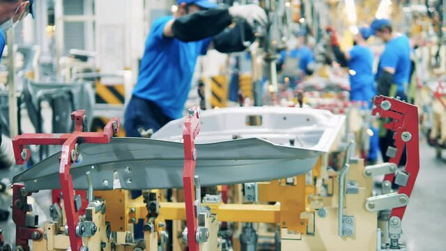Car manufacturing worker placing a car part on a welding machine