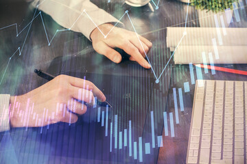 Double exposure of man's hands holding and using a phone and financial graph drawing. Analysis concept.