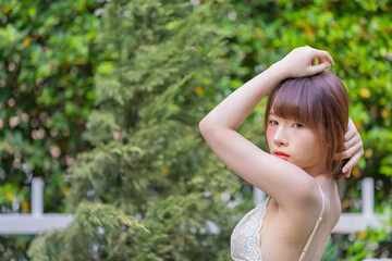Naklejka na ściany i meble Portrait of young pretty sexy Asian woman wearing bikini in garden.