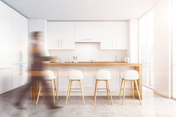 Man walking in white kitchen with bar