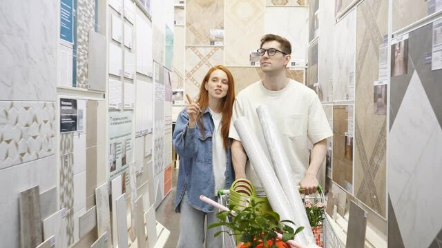 Couple choosing tiles for home, caucasian man and woman shopping together, redhead female points finger at the best one.