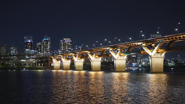 Subway train moving on illuminated Cheongdam Bridge At Night, Vehicles Passing By On Bridge Across Han River In Seoul, South Korea