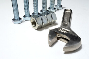 screw-nut of different sizes, bolts and adjustable spanner. White background.