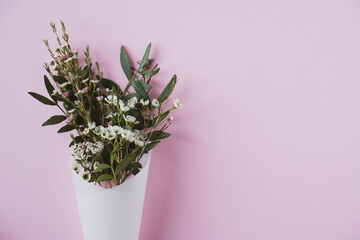 white flowers in paus tracing paper cone on pink background