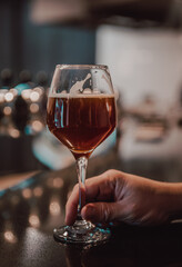 man holds a glass of beer in his hand at the bar or pub