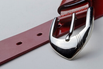 red women's belt with a chrome plaque on a white background. close-up.