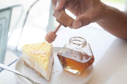 Hand holding honey syrup on cheese cake, Sweet and delicious. Coffee or cafe lifestyle