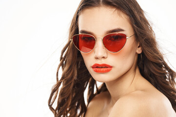 Portrait of brunette woman in sunglasses naked shoulders light background