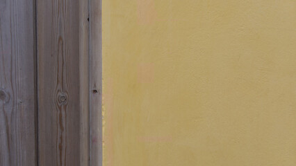 Background comprising vertical wooden planks and yellow plaster with copyspace