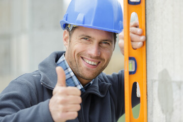 handsome man with thumb up holding building level