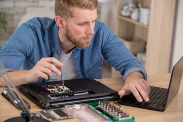 man repair laptop motherboard with screwdriver white coat