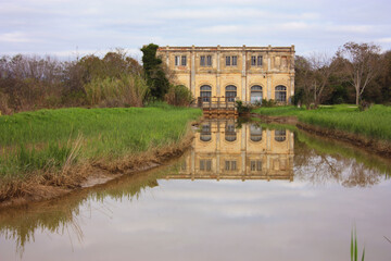 Obraz premium natural panorama with an ancient industrial structure the old dewatering building on the Arno river among the green grass