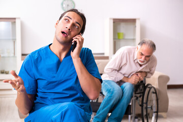 Old man in wheel-chair and young bad caregiver indoors