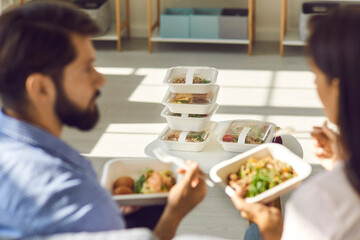 People eating healthy food from containers and discussing set of meals delivered for the whole day