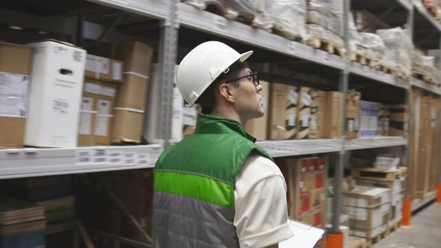 Young warehouse worker check quantity of commodity in big market, make notes if something is missing, check up, examine.