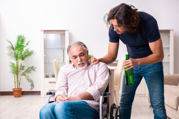 Obraz premium Old man in wheel-chair and young bad caregiver indoors