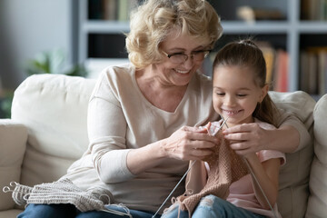 Happy proud elderly retired grandmother teaching little adorable preschool granddaughter creating...