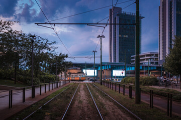 Fototapeta na wymiar Old tram passing at sunset near Piazza Gae Aulenti in the new and modern district of Porta Nuova in Milan. Sky with clouds
