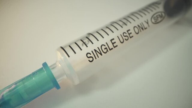 Disposable syringe with a needle on a white surface. The sign single use only. Rotating medicine part. Covid concept