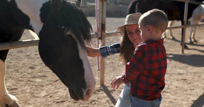 Mother and son having fun at farm ranch cuddling a horse