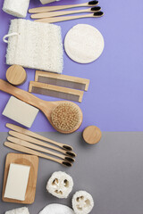 Fototapeta na wymiar Zero waste eco products with natural biodegradable accessories. Bamboo toothbrushes, handmade soap shampoo bars, cotton buds pads with charcoal and bicarbonate soda, luffa on grey purple, top view