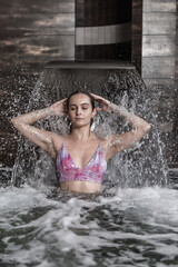 Relaxed woman enjoying splashing water stream in spa center