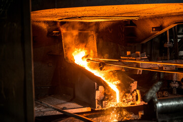 Pouring liquid metal from arc furnace. Production process in the steel mill.