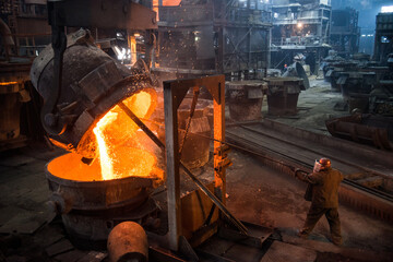 Steelworker at work near the tanks with hot metal