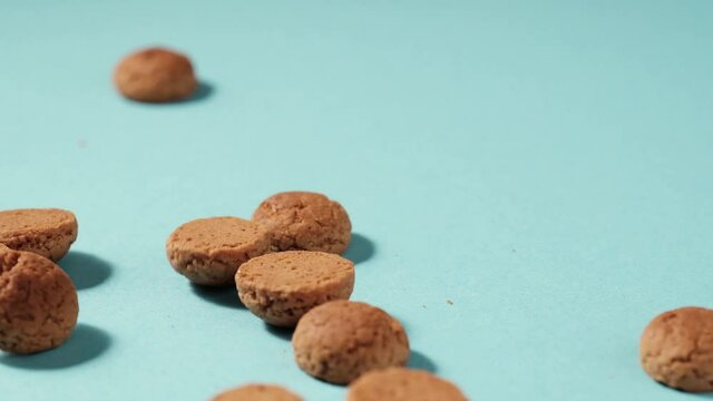 Scattered traditional dutch cookies kruidnoten gingersnap over blue background. St Nicholas day Sinterklaas in December, children holiday in Netherlands and Belgium. Full HD video, 100 fps slow motion