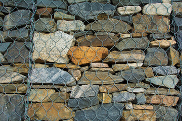 Background from natural stones closed with a metal mesh.