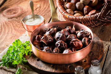 Roasted chestnuts on copper pan served with garlic dip