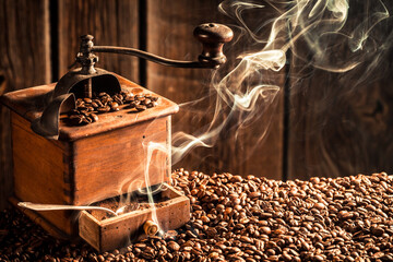 Old wooden coffee grinder on fresh roasted coffee grains