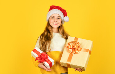 New year new me. time for discount. smiling kid hold purchase. presents and gifts santa claus. small girl santa at yellow background. xmas party celebration. happy new year. christmas shopping online