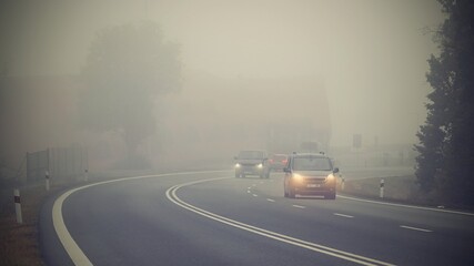 Car on the road in the fog. Autumn landscape - dangerous road traffic in winter season. - obrazy, fototapety, plakaty