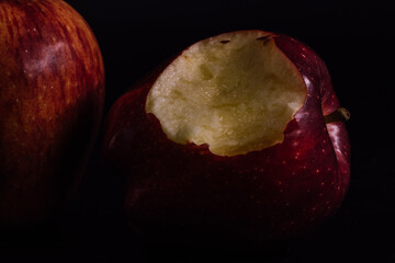 Red delicious apple with a bite missing on a black background