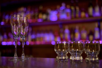  Two wine glasses filled with lights and three small spirits glasses in purple shimmering.