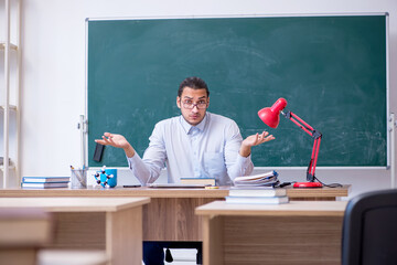 Young male teacher in front of green board