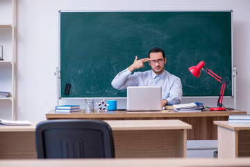 Young male teacher in front of green board