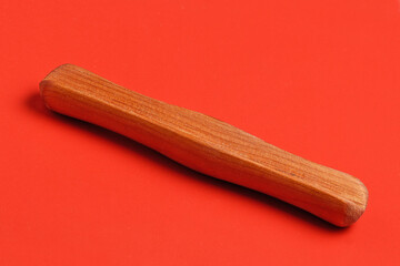 Traditional wooden handle for carrying cloth bags on a red background close-up
