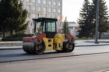 Asphalt road roller with heavy vibration roller compactor press new hot asphalt on the roadway on a road construction site. Heavy Vibration roller at asphalt pavement working. Repairing.