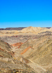 A trail running through a deserted rocky gorge with fantastic colors slopes.
